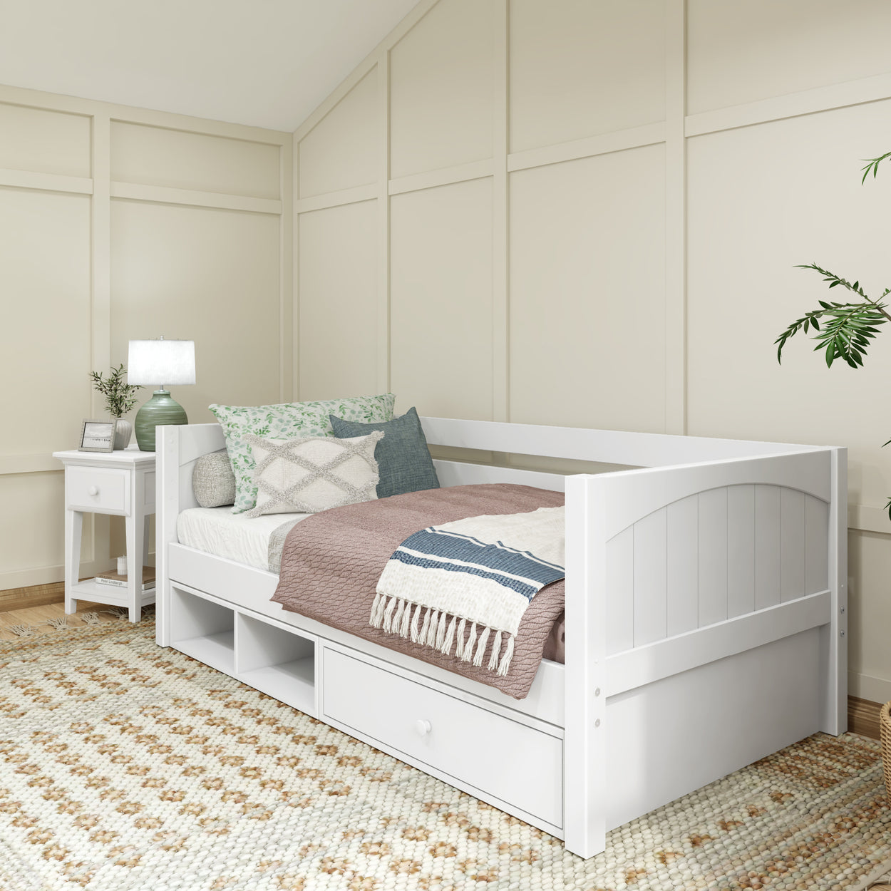 White wooden daybed with storage drawers in a cozy bedroom featuring a neutral-toned rug and decorative pillows.