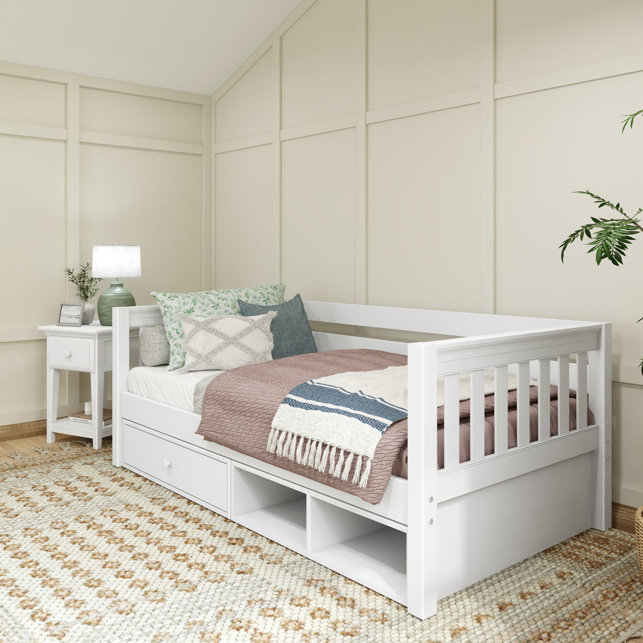 White wooden daybed with storage drawers, cozy pillows, and a throw blanket in a modern bedroom with beige walls and a geometric-patterned rug.