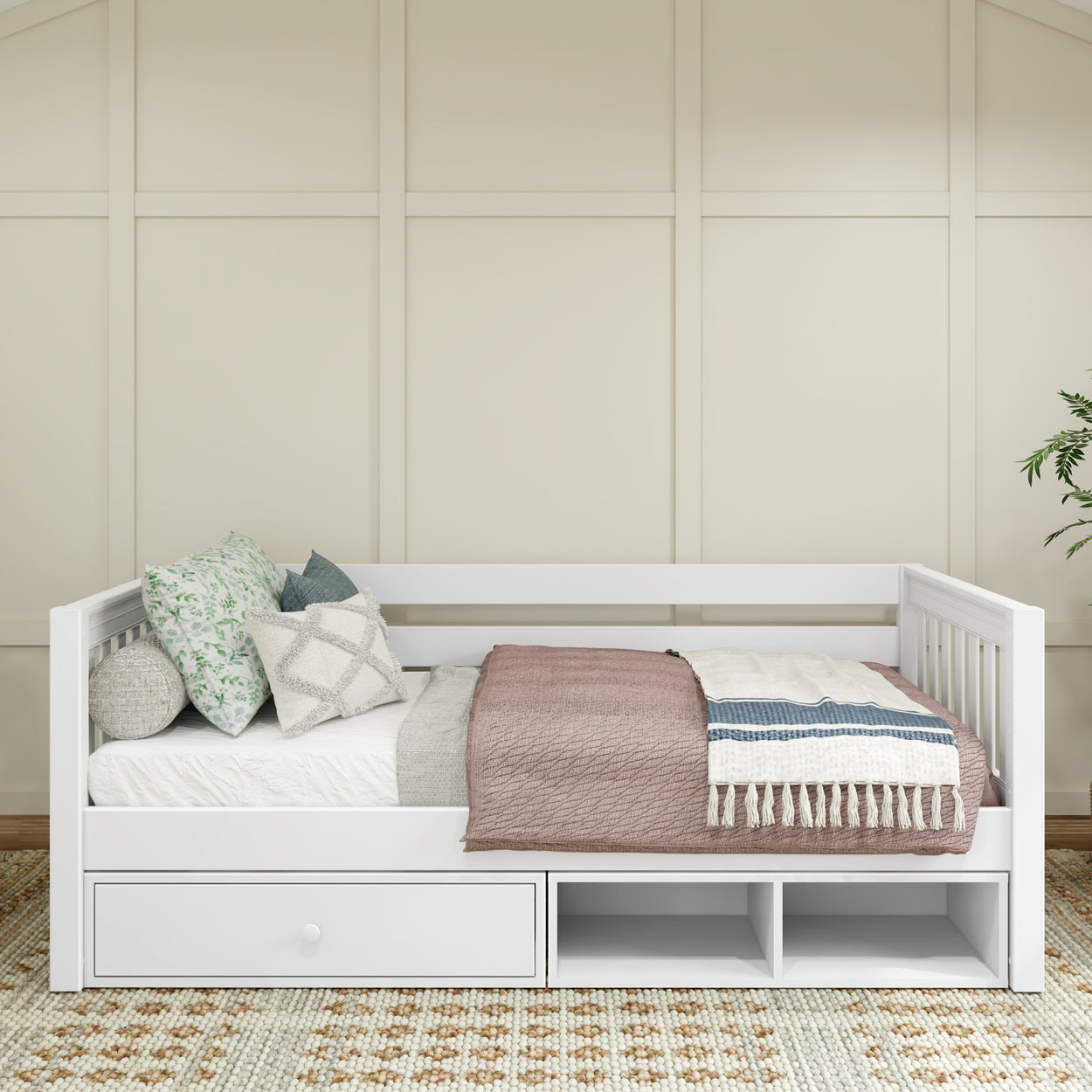 White wooden daybed with storage drawers, cozy knit blankets, and decorative pillows in a modern bedroom setting.