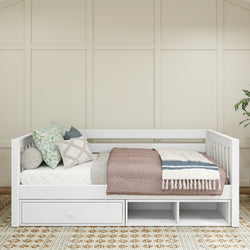 White wooden daybed with storage drawers, cozy knit blankets, and decorative pillows in a modern bedroom setting.