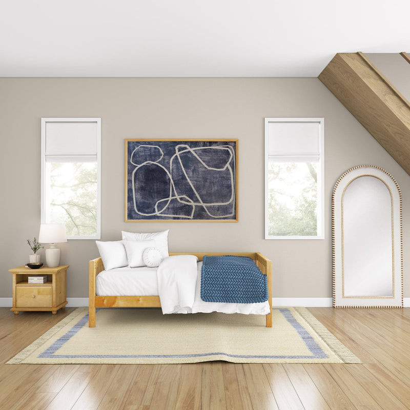 Cozy modern bedroom interior with wooden daybed, white bedding and blue knit throw, bedside table lamp, abstract wall art, arched mirror, neutral walls and hardwood floors