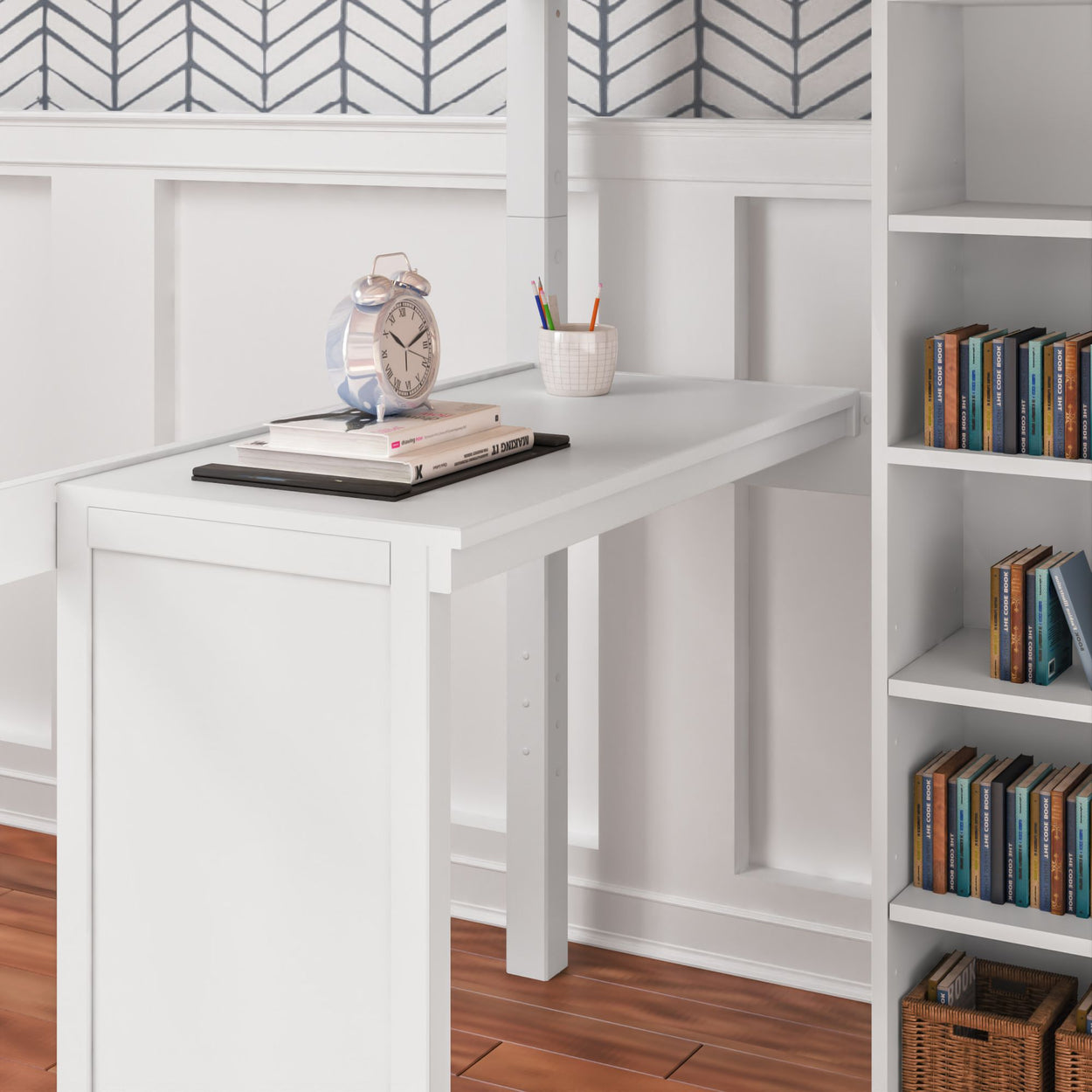White minimalist desk with books and a clock on hardwood flooring, next to a modern bookshelf and decorative wall paneling.
