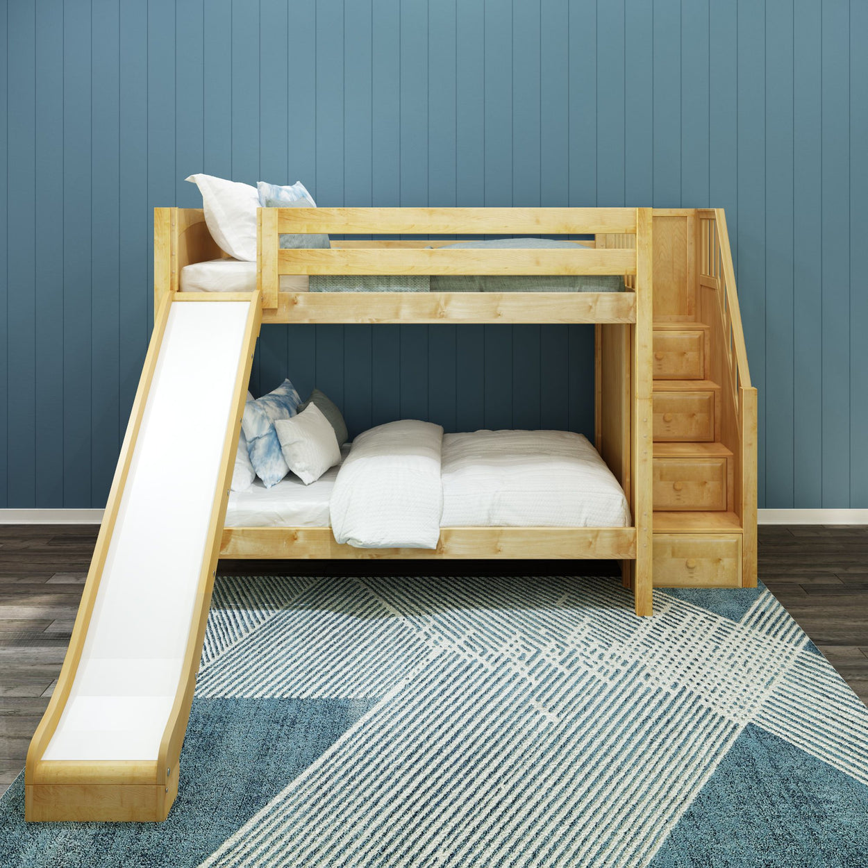 Wooden bunk bed with slide and stairs in front of blue wall, featuring white bedding on modern geometric rug.