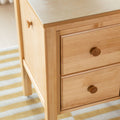 Close-up of light maple wood nightstand with round wooden knobs and three drawers, smooth natural finish for modern minimalist bedroom furniture