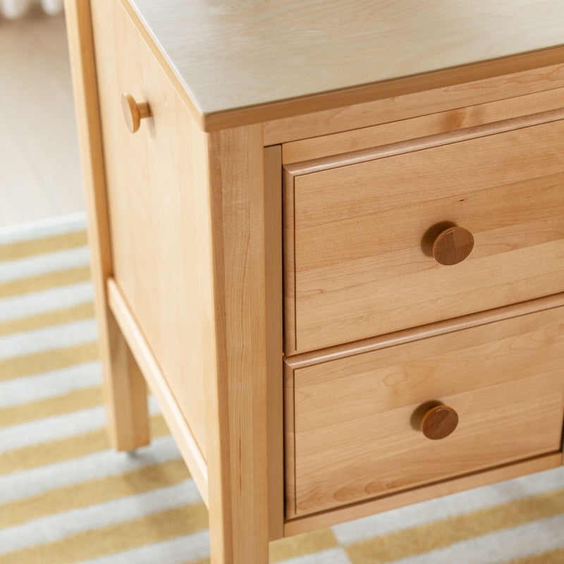 Close-up of light maple wood nightstand with round wooden knobs and three drawers, smooth natural finish for modern minimalist bedroom furniture
