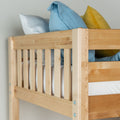Solid wood bunk bed frame close-up showing natural finish slatted guardrail with blue and yellow pillows