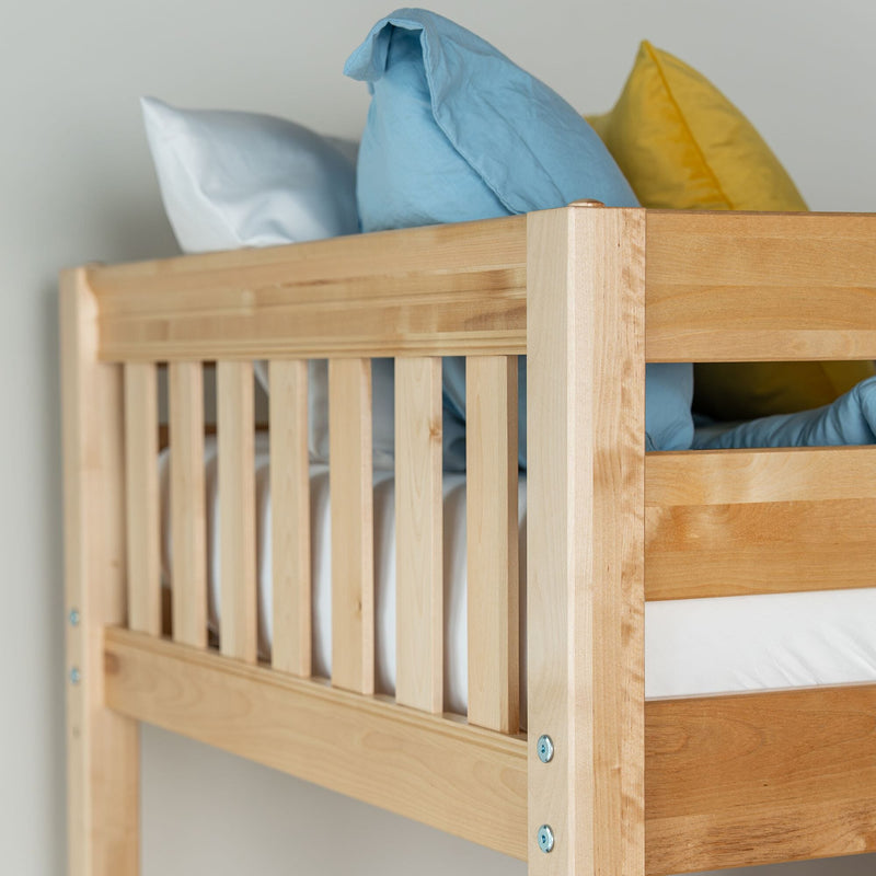 Solid wood bunk bed frame close-up showing natural finish slatted guardrail with blue and yellow pillows