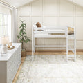 Neutral modern nursery with white wooden loft bed and ladder, white dresser, board-and-batten accent wall, potted plant, natural light