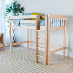 Natural wood twin loft bed with ladder in bright kids' bedroom, twin-size elevated wooden bed with blue bedding, yellow accent pillow, striped rug and potted plant