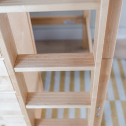Wooden bunk bed ladder with light natural slatted steps, close-up in a modern kids' bedroom interior with striped rug