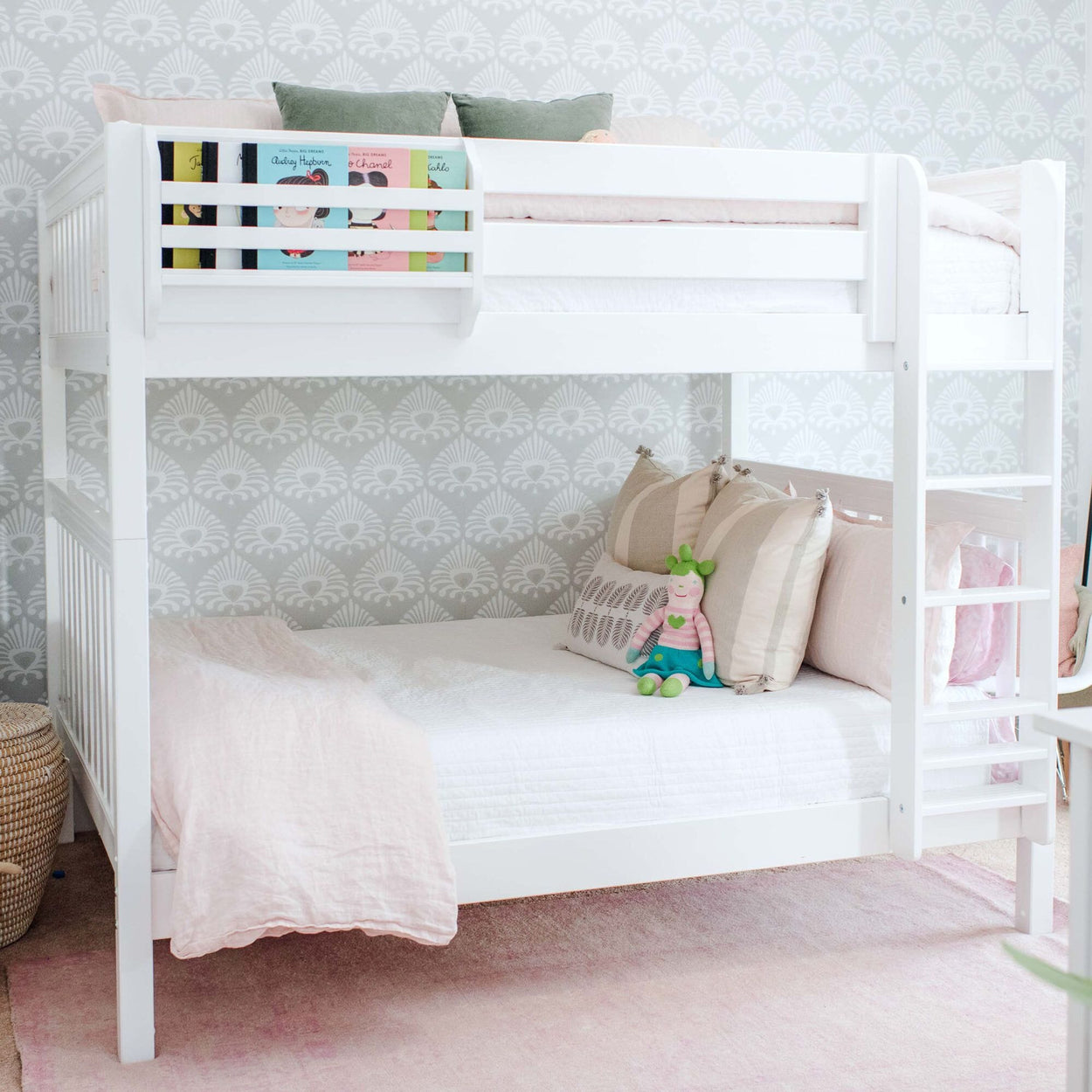 White wooden bunk bed with pink bedding, plush doll and ladder against gray patterned wallpaper in a children's nursery