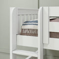 Close-up of white wooden bunk bed ladder and guardrail with blue-striped quilt and tasseled blanket, modern kids loft bed interior