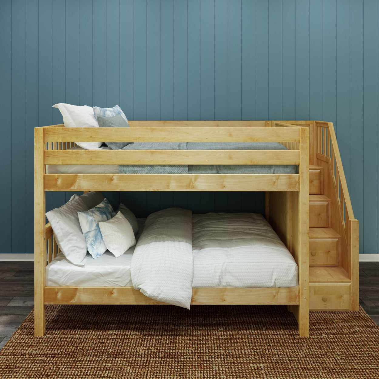 Natural pine twin-over-full bunk bed with built-in storage stairs, white bedding and throw pillows against blue paneled wall in a modern kids' bedroom