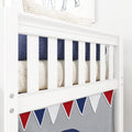 White wooden crib rail with navy cushion, cream knit blanket and red-white-blue pennant bunting nursery decor