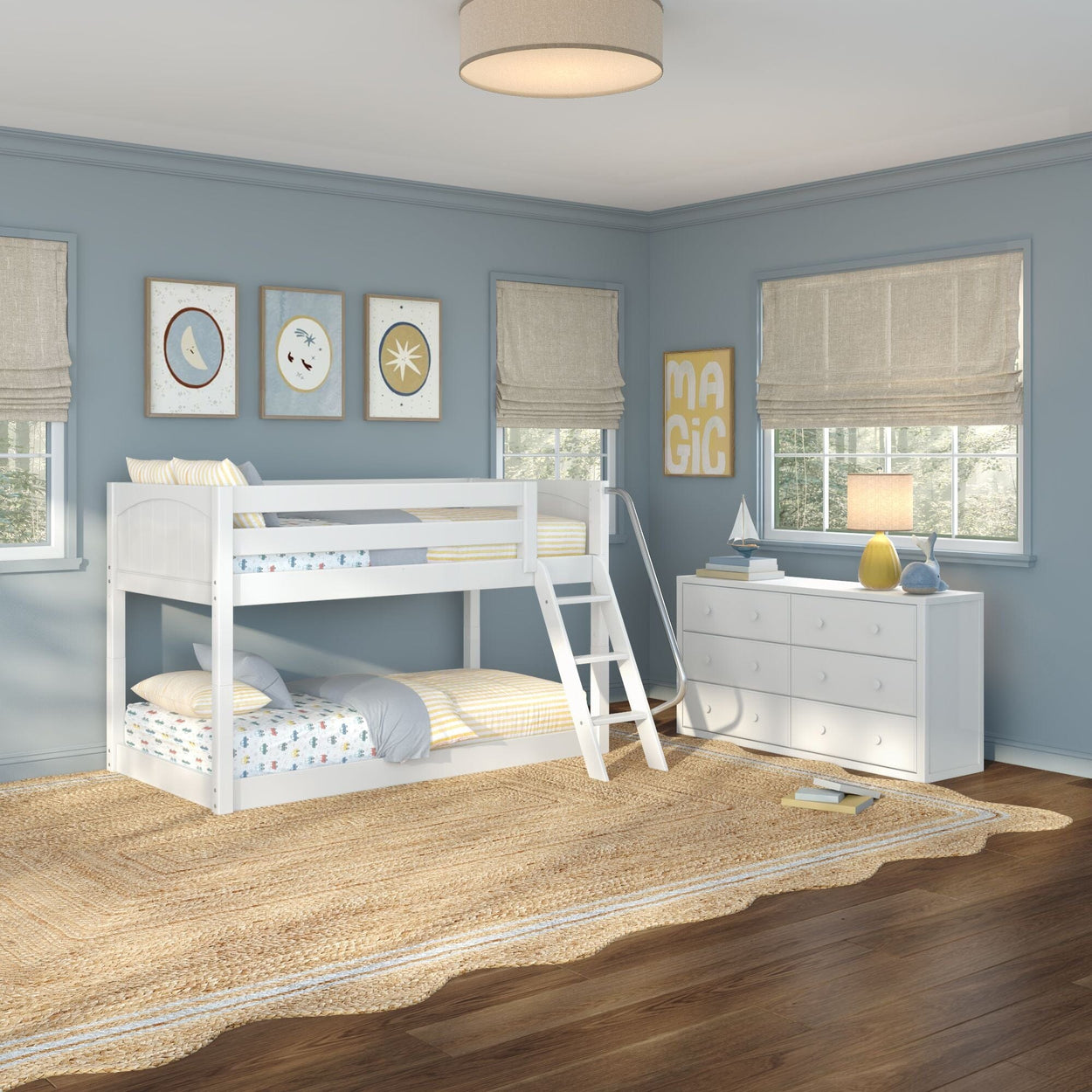 White twin-over-twin bunk bed with ladder and slide in a light-blue kids' bedroom with white dresser, natural jute rug, roman shades and playful wall art