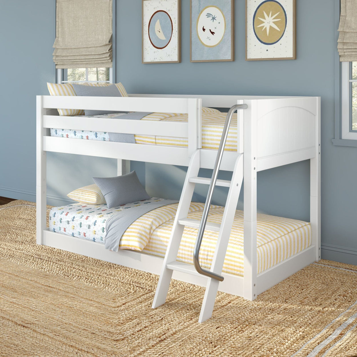 White wooden bunk bed with angled ladder in a children's blue bedroom, yellow-striped bedding, gray pillows, coastal framed wall art and woven jute rug