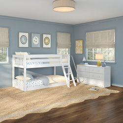 Bright coastal-style children's bedroom with a white twin-over-twin bunk bed featuring ladder and slide, blue walls with moon and star prints, natural jute area rug on wood floors, white six-drawer dresser with lamp and sailboat decor, and neutral roman shades.