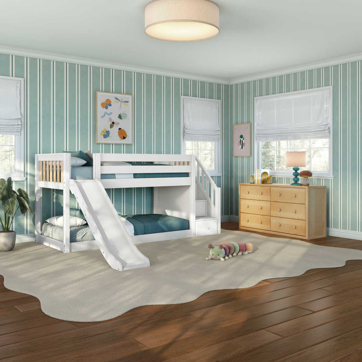 Bright kids' bedroom with white wooden bunk bed and slide, blue striped wallpaper, wooden dresser, hardwood floors and plush rug