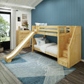 Wooden kids bunk bed with slide and storage staircase in a modern children's bedroom with blue accent wall, dresser and patterned rug