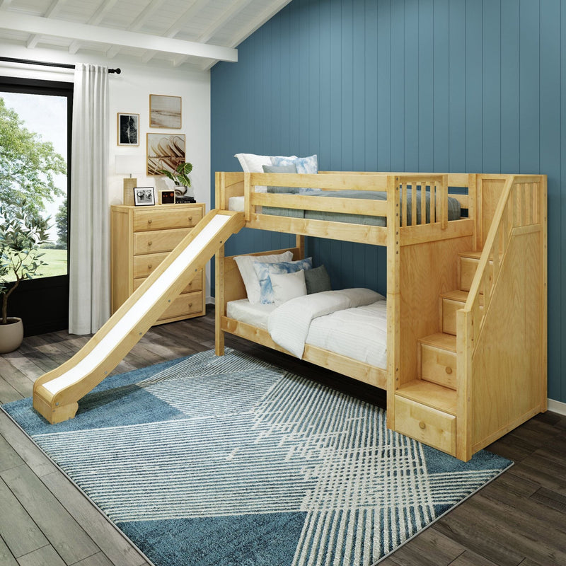 Wooden kids bunk bed with slide and storage staircase in a modern children's bedroom with blue accent wall, dresser and patterned rug