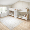 White wooden twin bunk beds in a bright neutral kids bedroom with board-and-batten accent wall, large window, dresser and area rug