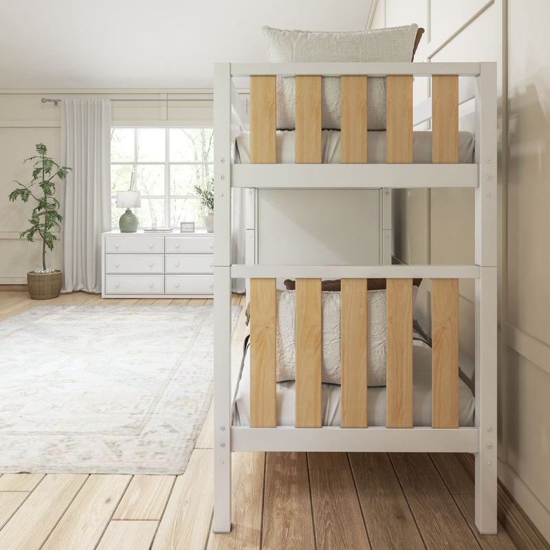Bright neutral kids bedroom with white wooden bunk bed featuring natural wood slats, white dresser under large window, table lamp and potted plant