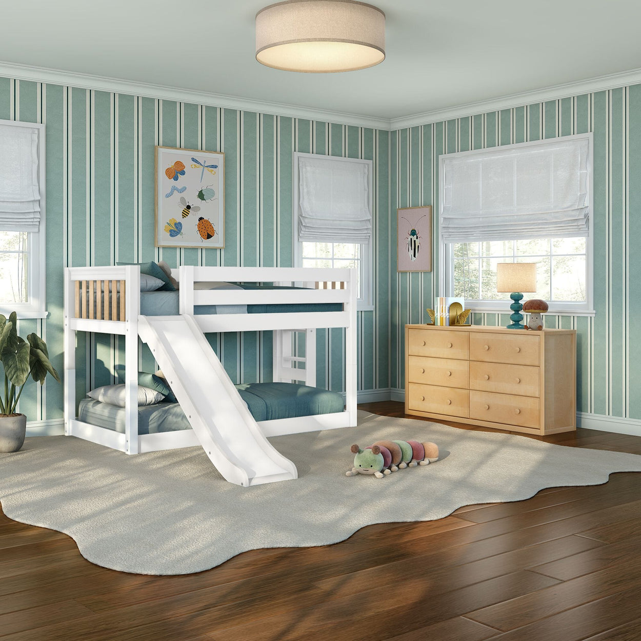 White wooden kids bunk bed with slide in a bright children's bedroom featuring teal striped wallpaper, wooden dresser, plush caterpillar toy, and hardwood floors