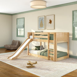 Natural wood twin-over-twin bunk bed with slide and ladder in bright kids' bedroom with green bedding, plush toys, framed wall art and wooden toy airplane on rug