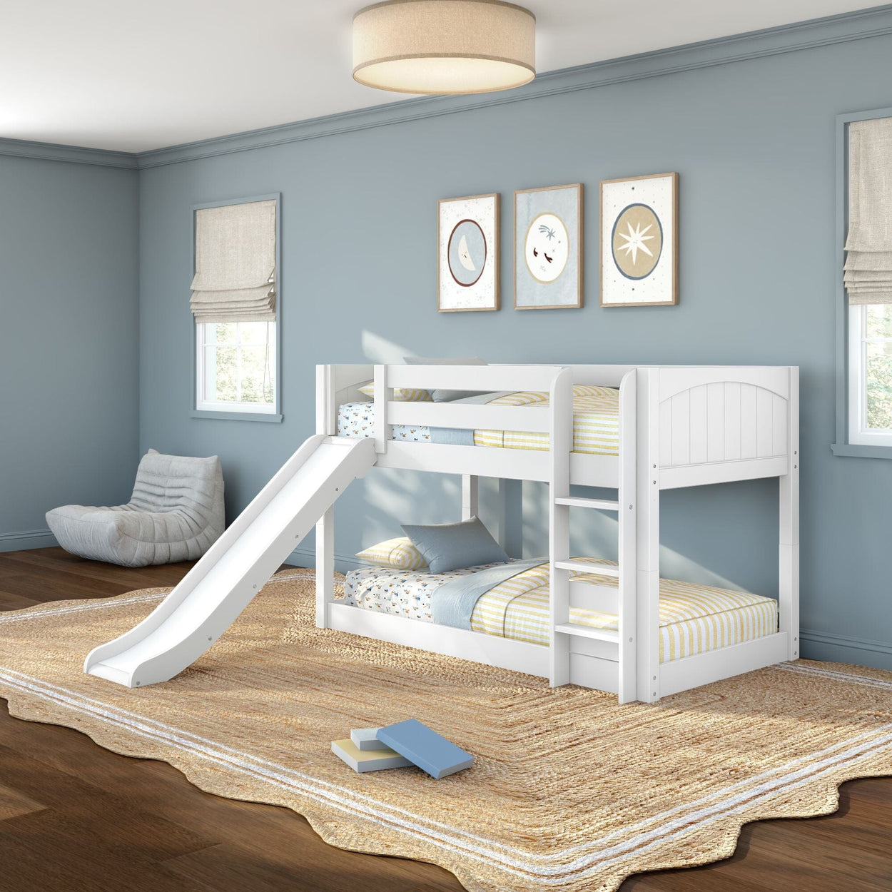 White twin-over-twin bunk bed with slide and ladder in a light blue kids' bedroom, striped bedding, natural jute rug and framed wall art