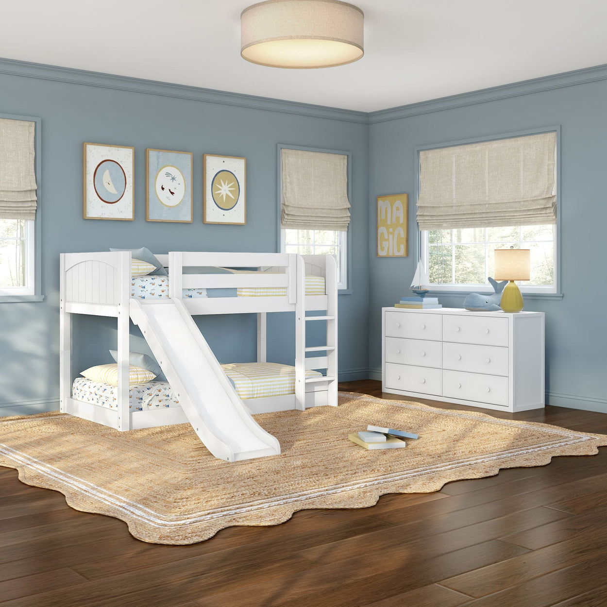 White wooden bunk bed with slide and ladder in a coastal blue kids' bedroom with white dresser, nautical wall art, natural jute rug and hardwood floors