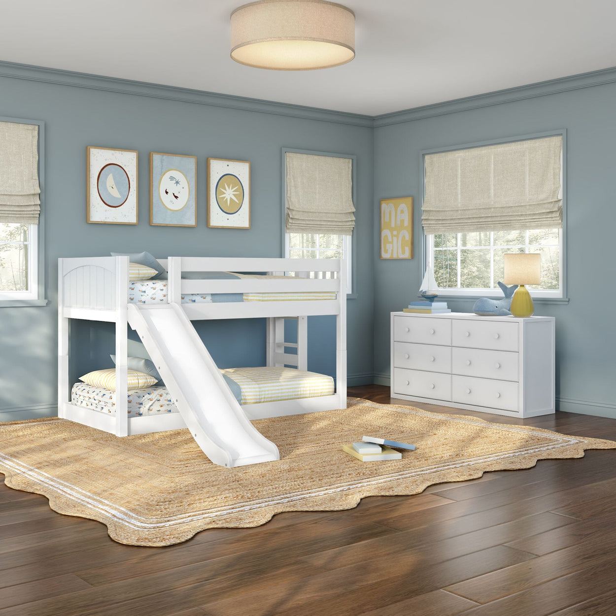 White twin-over-twin bunk bed with slide in a coastal blue kids' bedroom with white dresser, beige roman shades, natural jute rug on hardwood floors and modern children's room décor