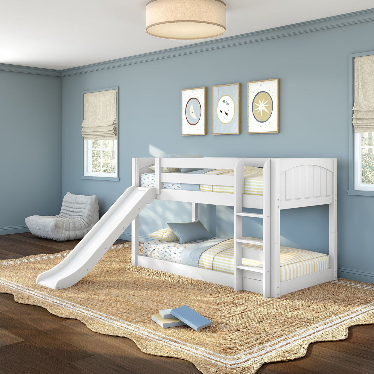 White wooden twin bunk bed with slide and ladder in a light-blue kids' bedroom featuring striped bedding, natural jute rug, hardwood floors, roman shades and framed wall art