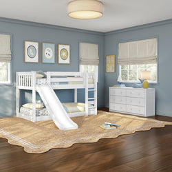 White twin-over-twin bunk bed with slide in a light-blue children's bedroom featuring framed wall art, beige Roman shades, white dresser with lamp and nautical decor, woven jute rug and hardwood floors