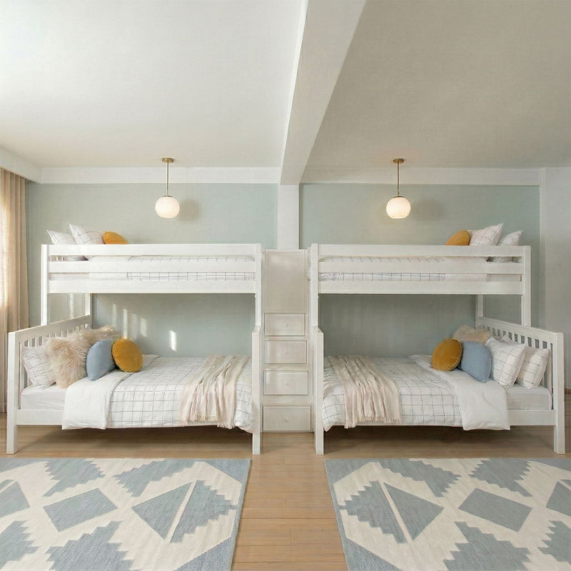 White twin bunk beds in a shared kids' bedroom with pastel pillows, hanging globe lights, center ladder and geometric rug
