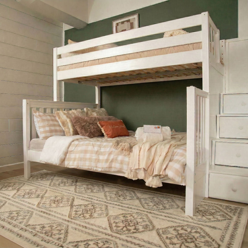 White wooden twin-over-full bunk bed with stair storage, beige plaid bedding and cozy decorative pillows in a farmhouse-style kids' bedroom with patterned area rug