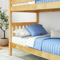 Natural wood bunk bed with blue quilt and star-print sheets in a modern kids' bedroom with potted plant and light rug