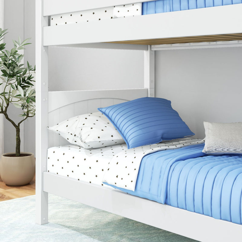White twin wooden bunk bed with blue quilted comforter, star-print white sheets and pillows in a modern kids' bedroom with potted plant