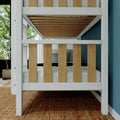 White wooden bunk bed with natural wood slats in a modern kids' bedroom with blue accent wall, woven rug, potted plant and cozy bedding