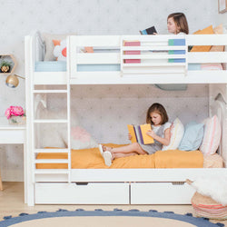 Children reading books on a white bunk bed with colorful pillows and modern room decor.