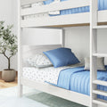 White wooden bunk bed with blue quilted bedding and star-print sheets in a modern kids' bedroom with potted plant