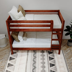 Wooden bunk bed with white bedding in a cozy bedroom interior featuring a patterned rug and modern decor.