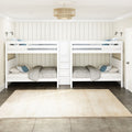 White wooden twin-over-twin bunk beds in a coastal farmhouse kids bedroom with shiplap paneled walls, center storage ladder with drawers, neutral gray bedding, blue accent pillows, wall-mounted reading lamps, rattan pendant light and beige area rug