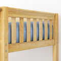 Close-up of natural light-wood bed frame rail with vertical slats, exposed hardware, and blue mattress