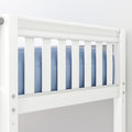 Close-up of white wooden crib slatted railing with blue mattress bedding in a modern nursery
