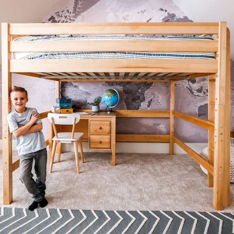 Natural wood loft bed with built-in desk and study nook, striped mattress, globe and world map wallpaper in a space‑saving bedroom with a smiling person.