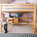 Natural wood kids loft bed with built-in desk and drawers, twin mattress with striped bedding, globe and world-map wallpaper in study area, smiling boy standing nearby