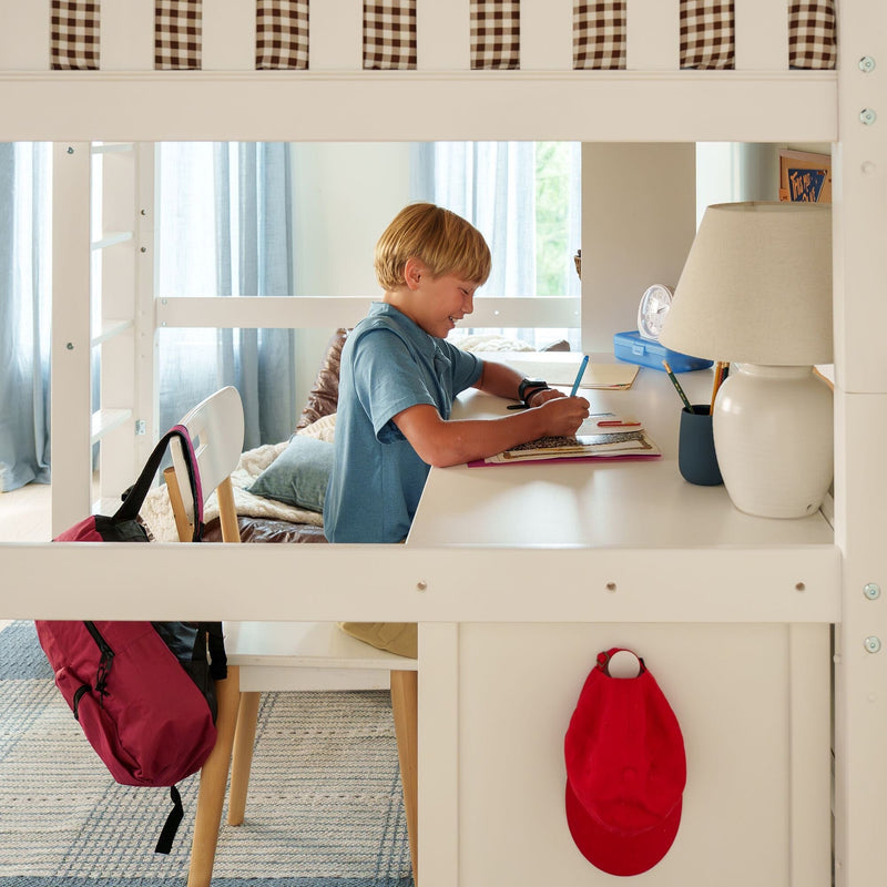 Boy studying at a white loft-bed desk in a bright kids' homework workspace with backpack, lamp, and clock