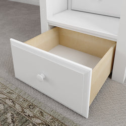 Open wooden drawer in modern white cabinet on carpeted floor.
