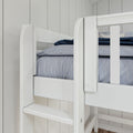 Close-up of white wooden bunk bed guardrail and ladder with blue-gray bedding against light gray shiplap wall in a modern kids' bedroom