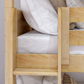 Wooden bunk bed ladder and guardrail close-up with white striped bedding, cozy textured pillows and natural pine finish